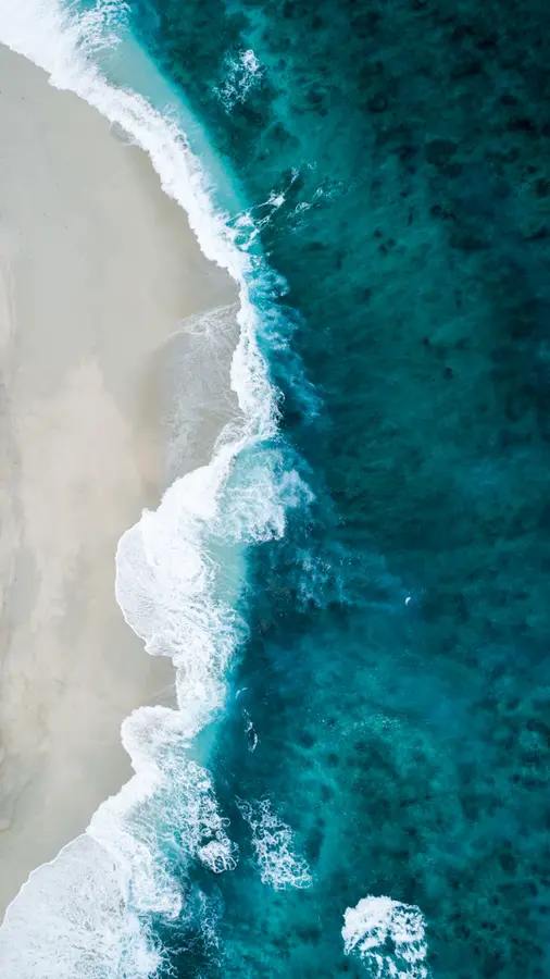 Vue aérienne de vagues sur une plage de sable blanc